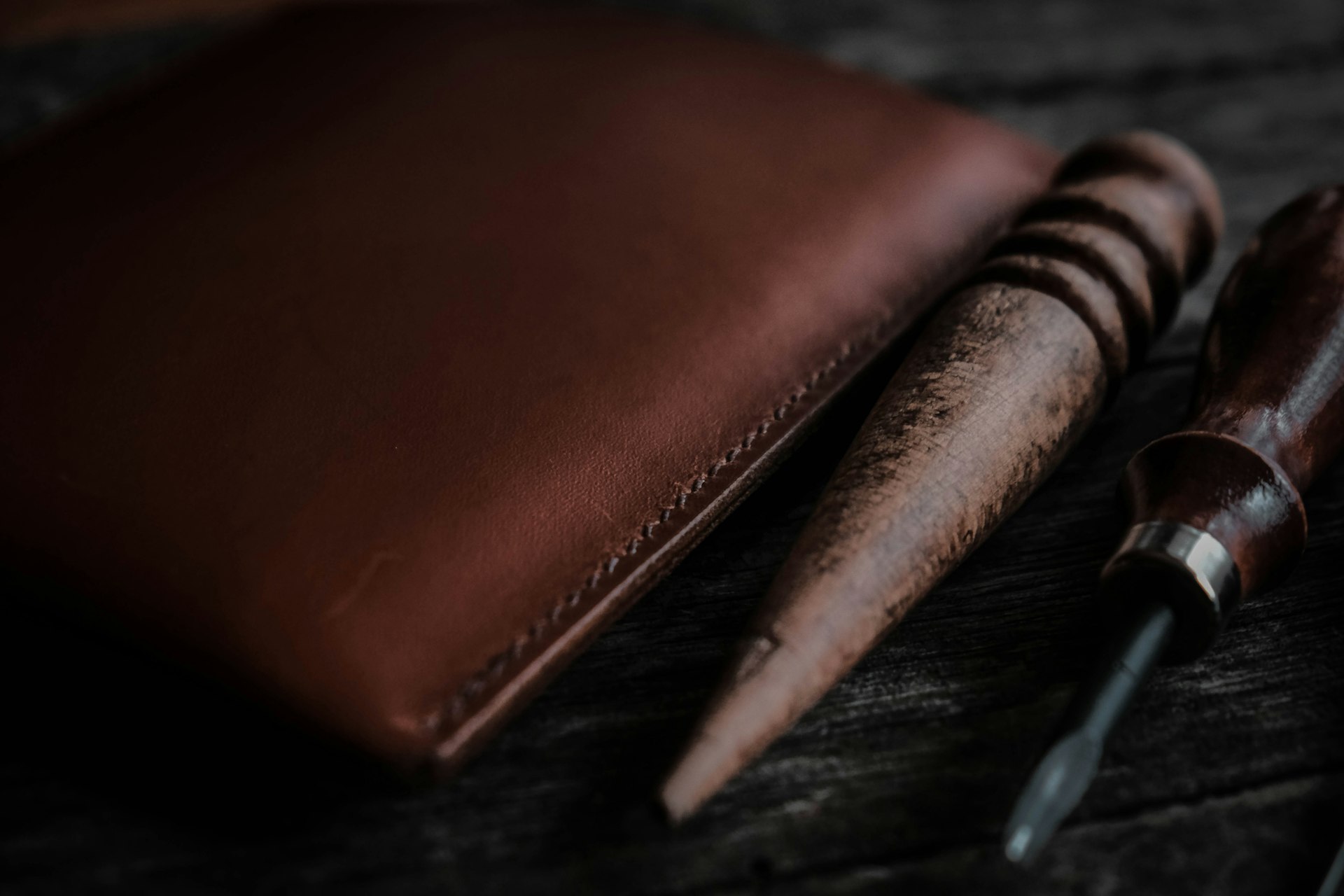 Leather wallet edge beside a stitching awl