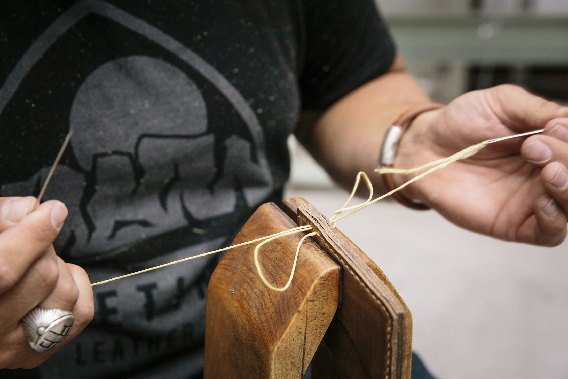 Hands stitching leather with waxed thread